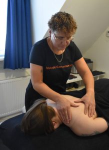 Vrouw op massagetafel van Musclecare Meppel die een schoudermassage krijgt